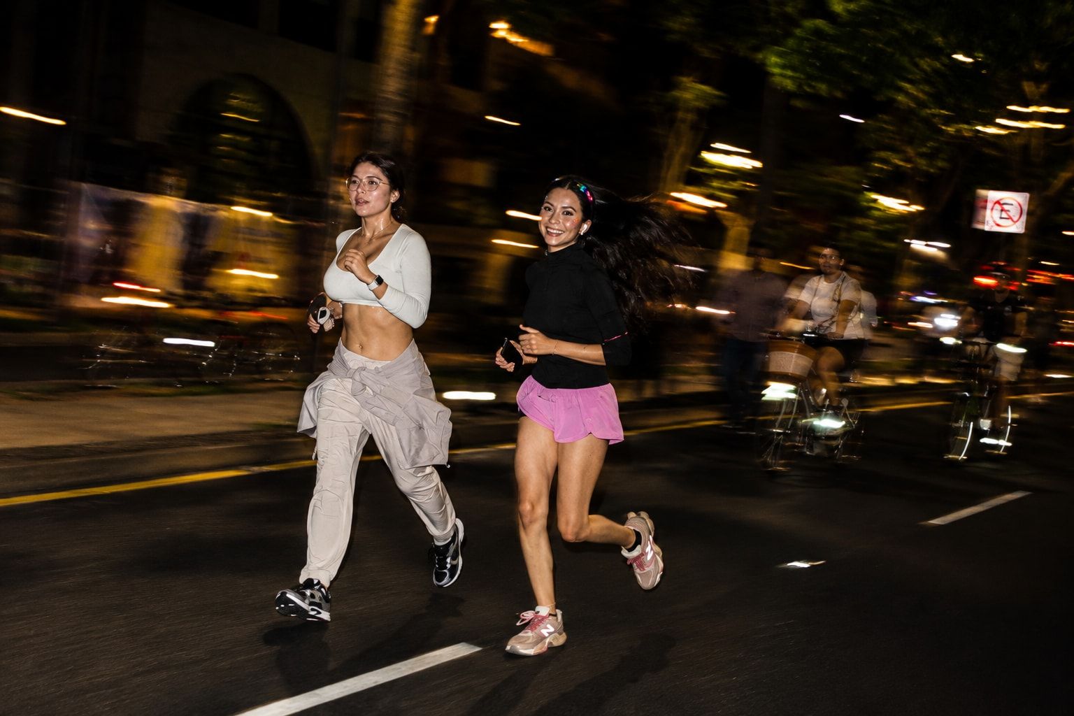 Two runners running side by side down the avenue at night