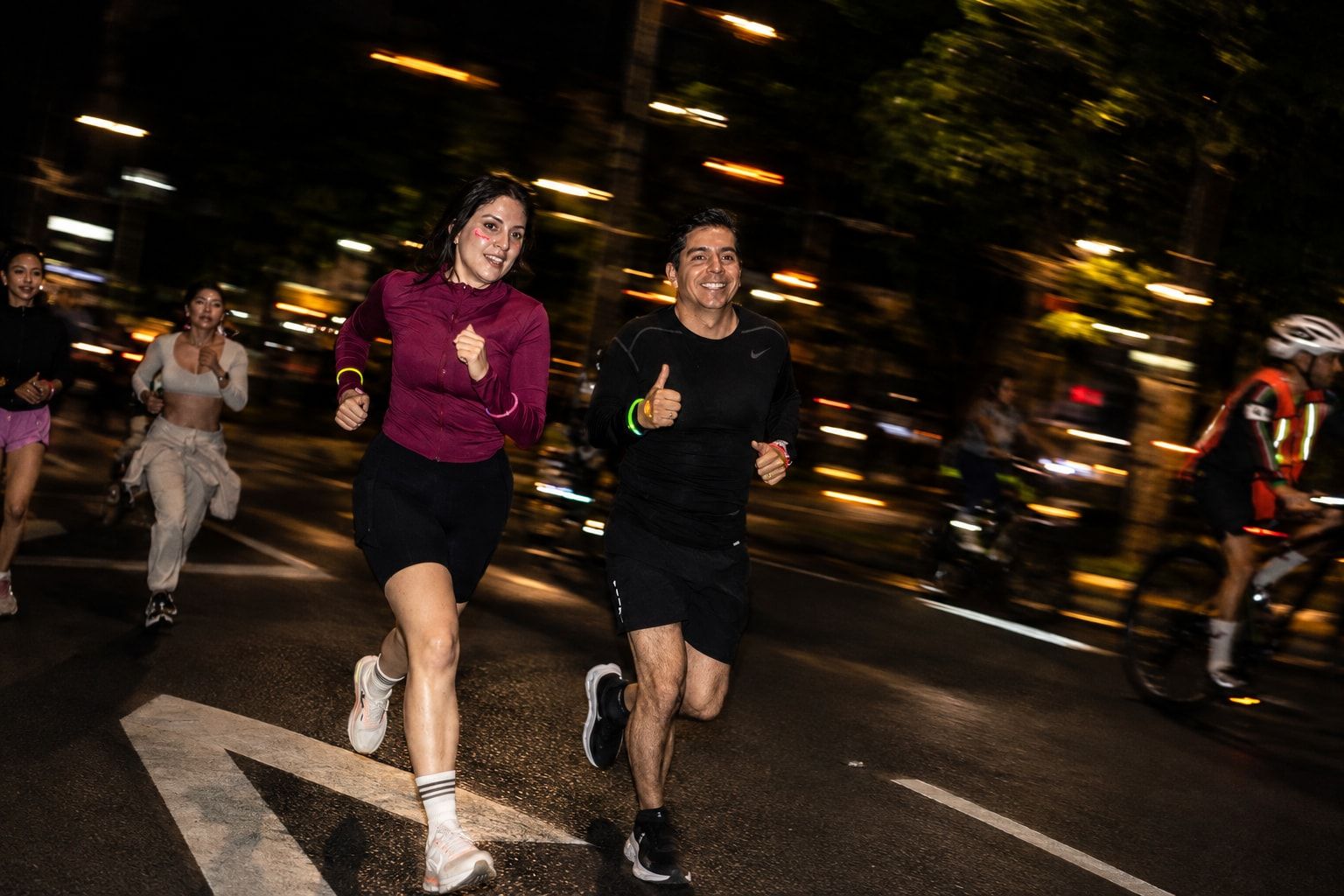Two runners smiling and giving a thumbs-up mid-run