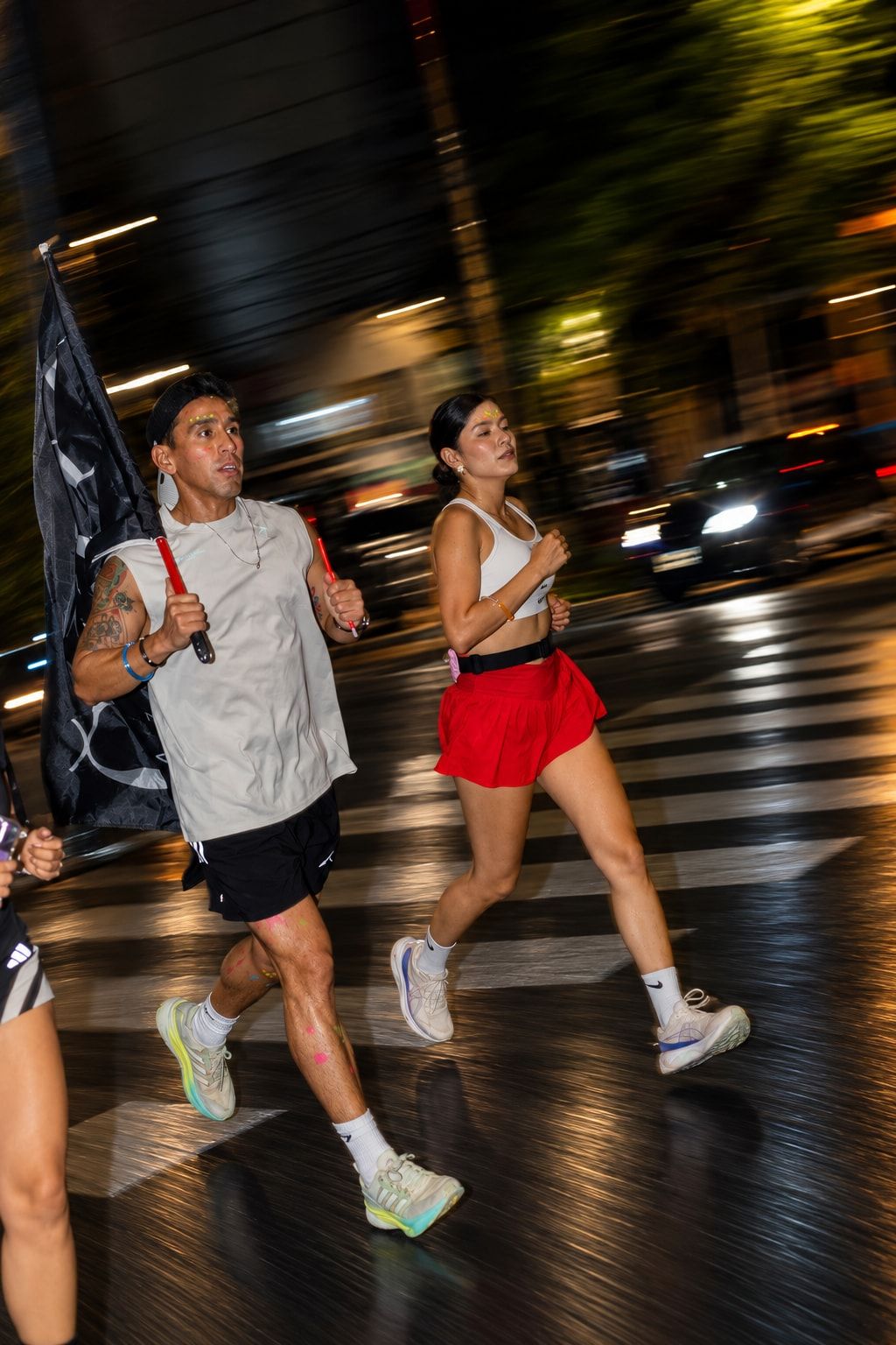 Runner with the Yelo flag and a runner in a red skirt crossing the avenue
