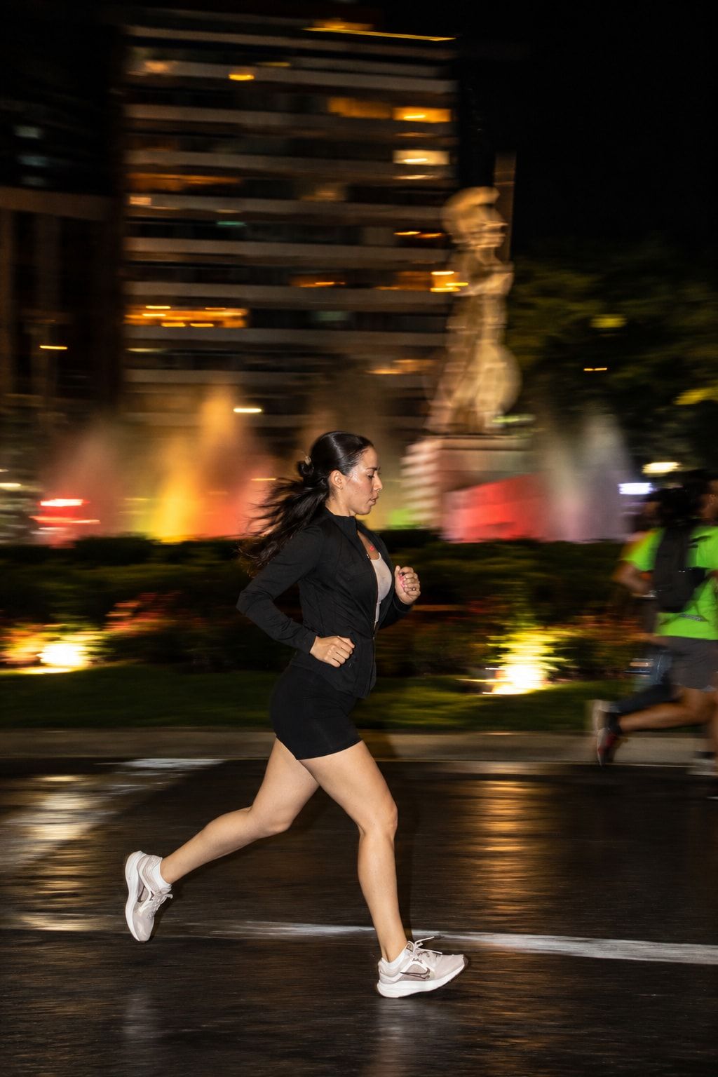 Runner passing the illuminated La Minerva fountain